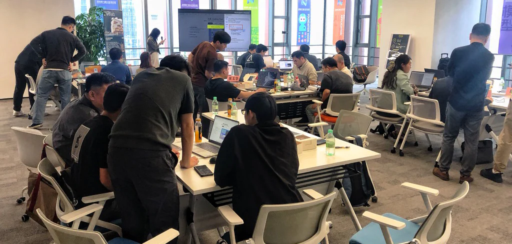 AI 行业分享交流现场照片：参与者围桌使用电脑，进行操作与交流。